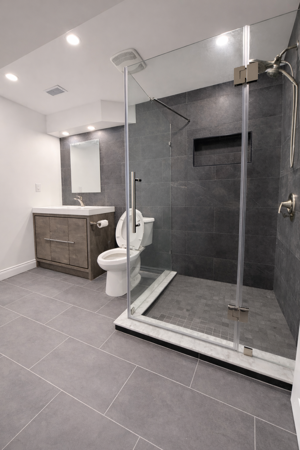 Modern basement bathroom with glass shower and large format tile in West Island Montreal