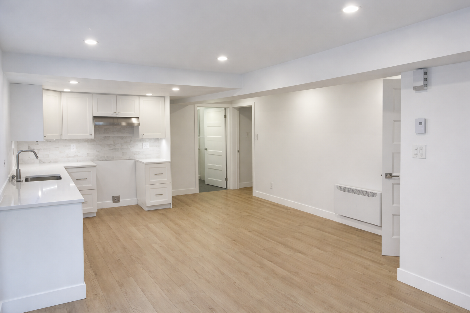 Basement kitchenette renovation with white cabinets and modern flooring in West Island Montreal