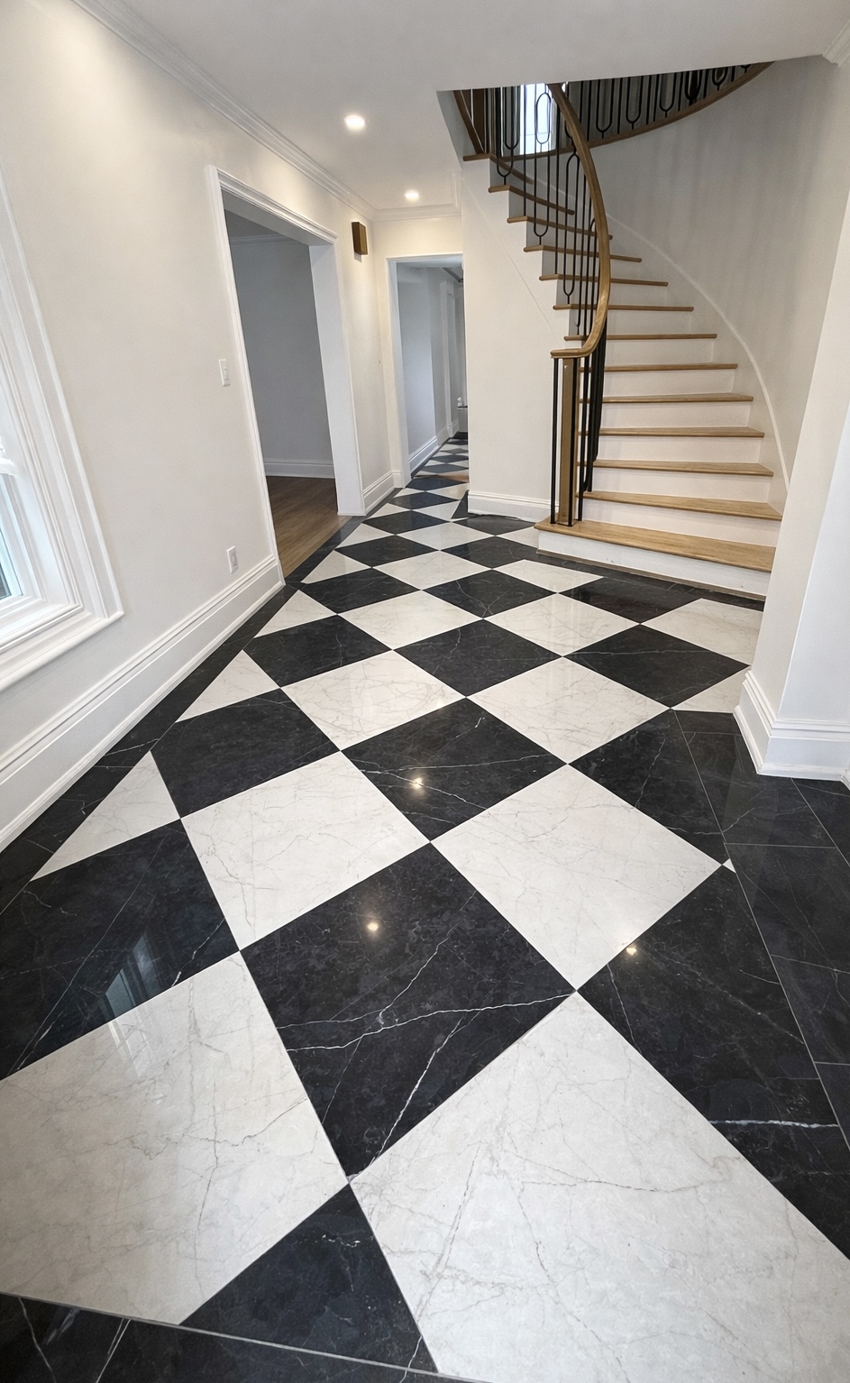 Entryway renovation in West Island Montreal featuring black and white tile flooring, custom staircase with wood steps and iron railings, serving Dorval, Pointe-Claire, Pierrefonds, Kirkland, Beaconsfield, Dollard-Des-Ormeaux and Vaudreuil-Dorion