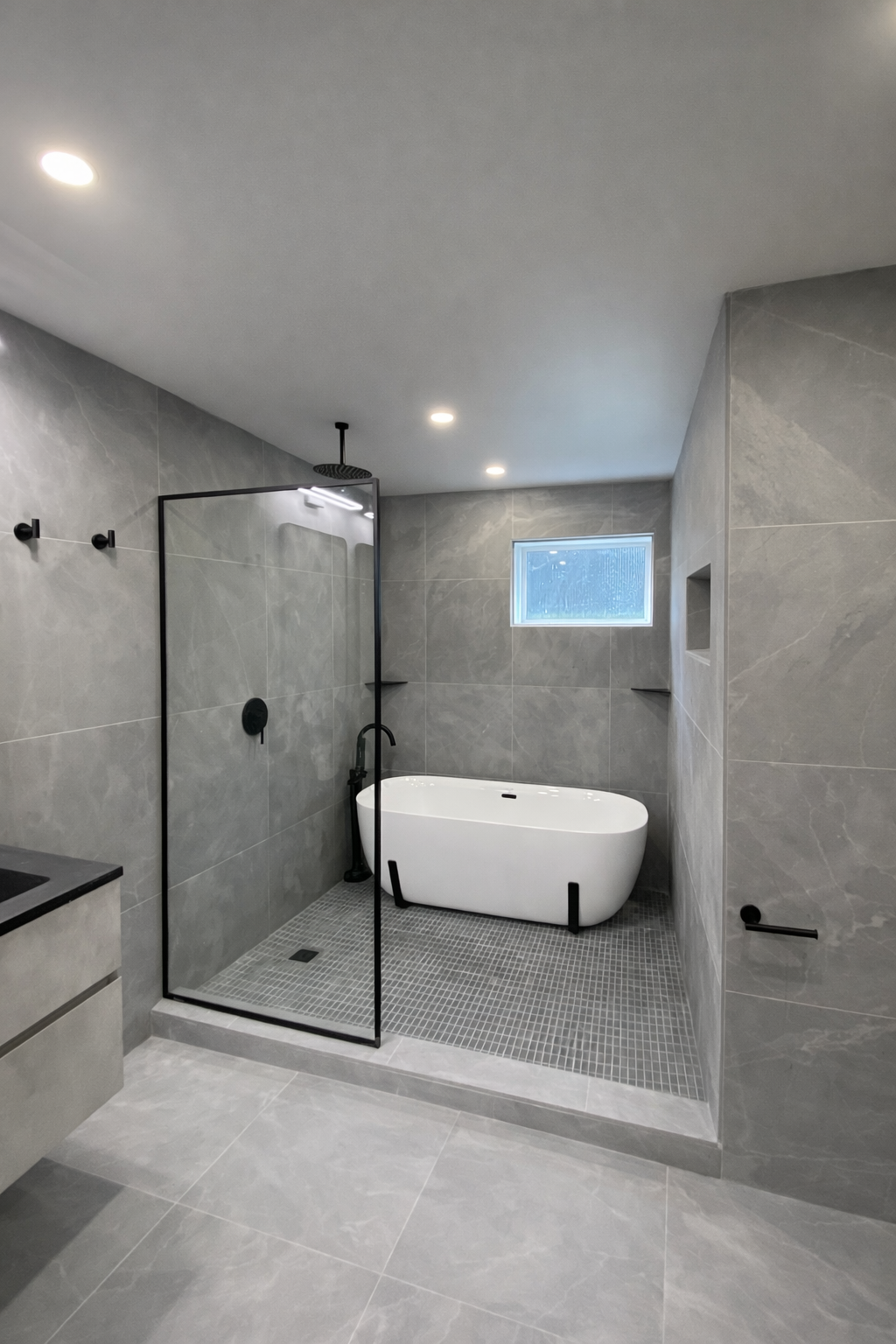 Modern bathroom with integrated glass shower and freestanding tub design with gray tile in West Island Montreal