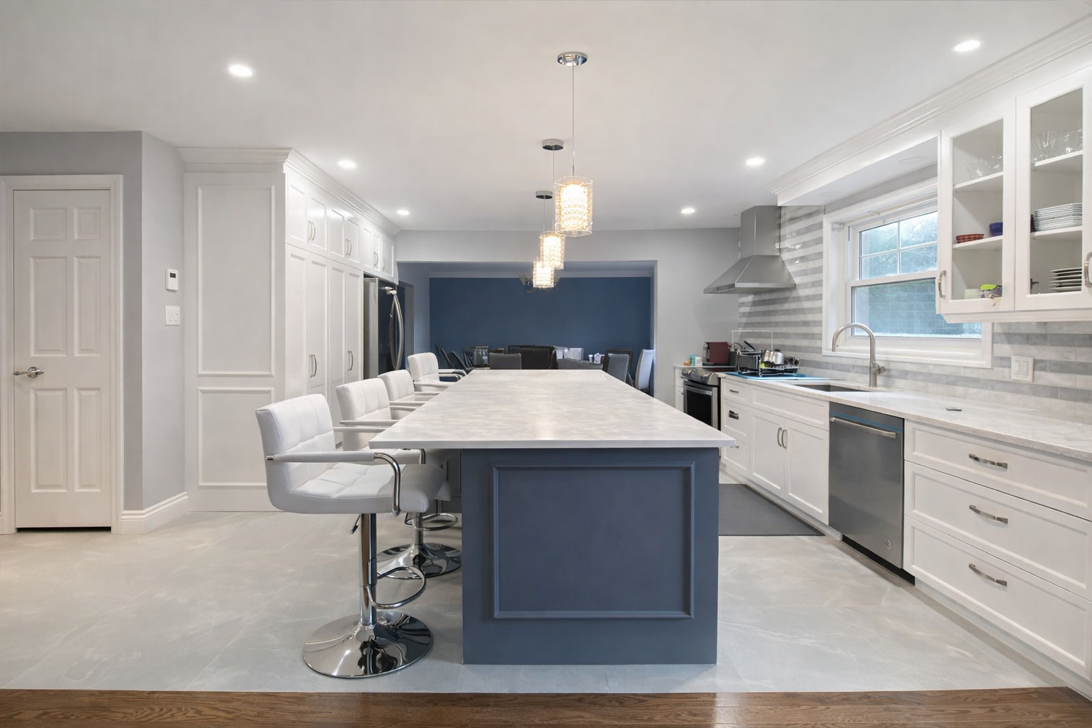 Modern kitchen renovation in West Island Montreal with blue island, white cabinets, large seating area and quartz countertops